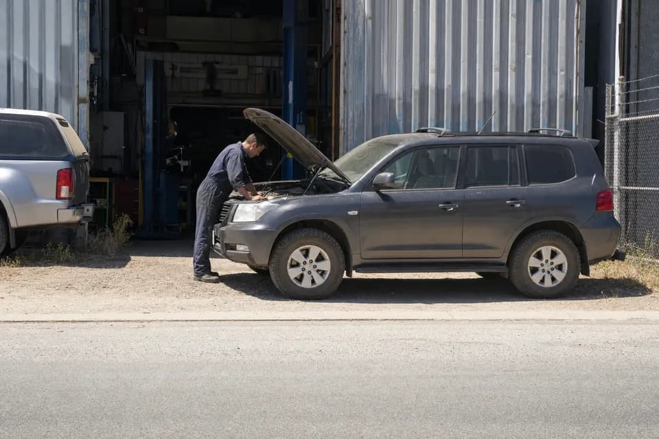 A car with its bonnet up being checked outside a workshop