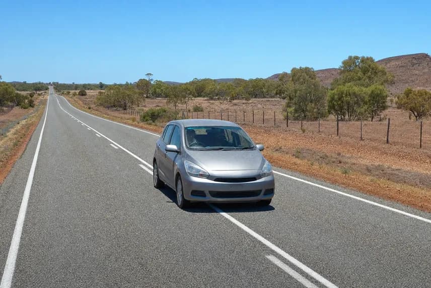Small silver hatchback on an empty outback highway