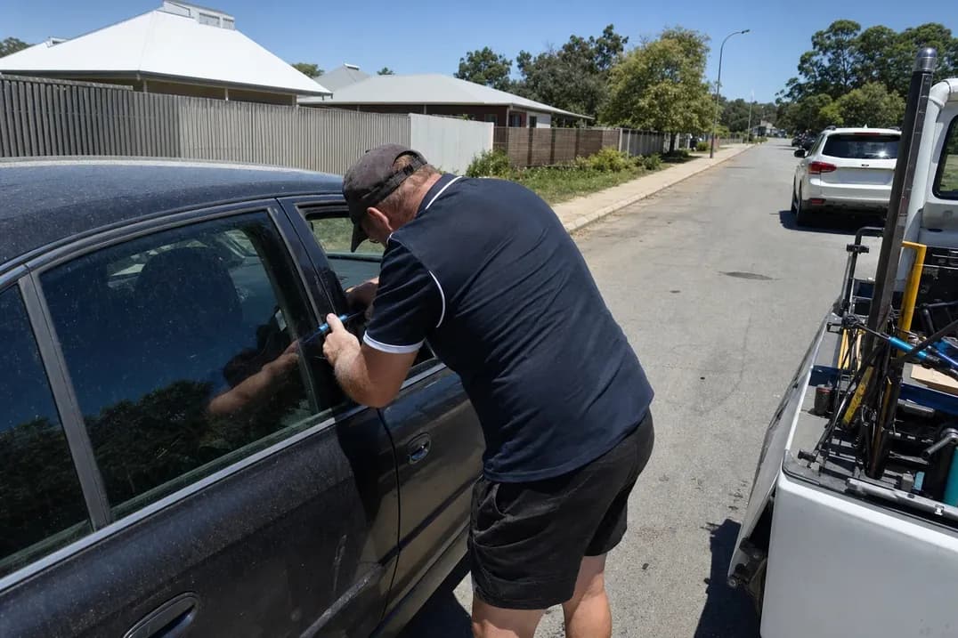 Man forcing a tool into the door frame of a locked sedan