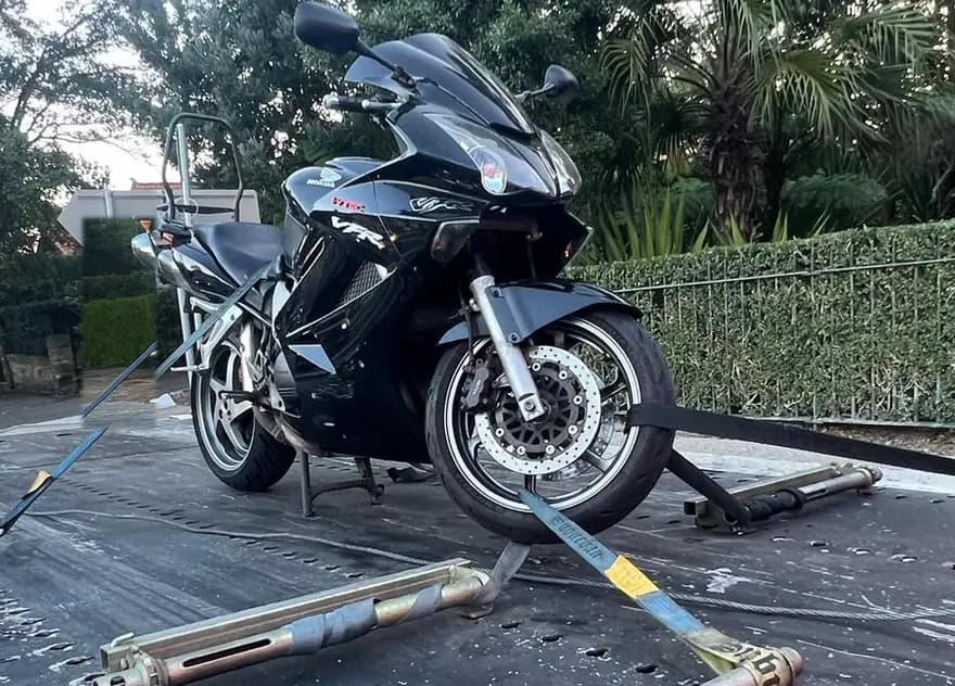 Black Honda VFR sports bike strapped down on a tilt tray deck