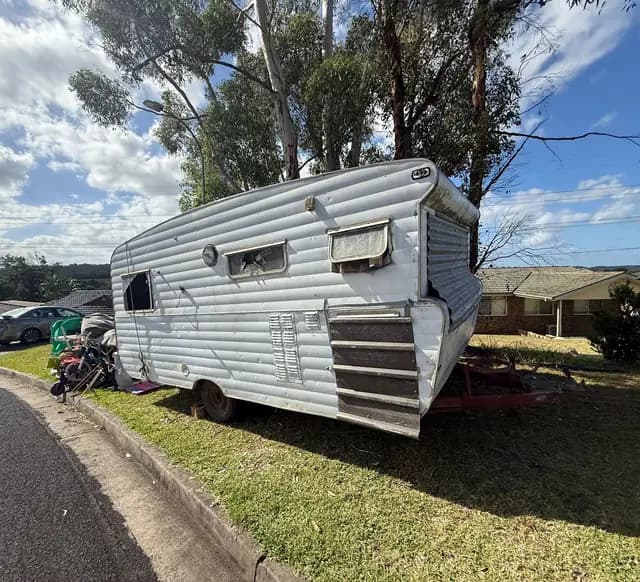 Old caravan parked on a grass verge waiting to be towed