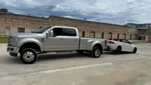 White BMW convertible on the wheel lift behind the Quokka Towing dual-wheel Ford beside the limestone wall of Fremantle Prison