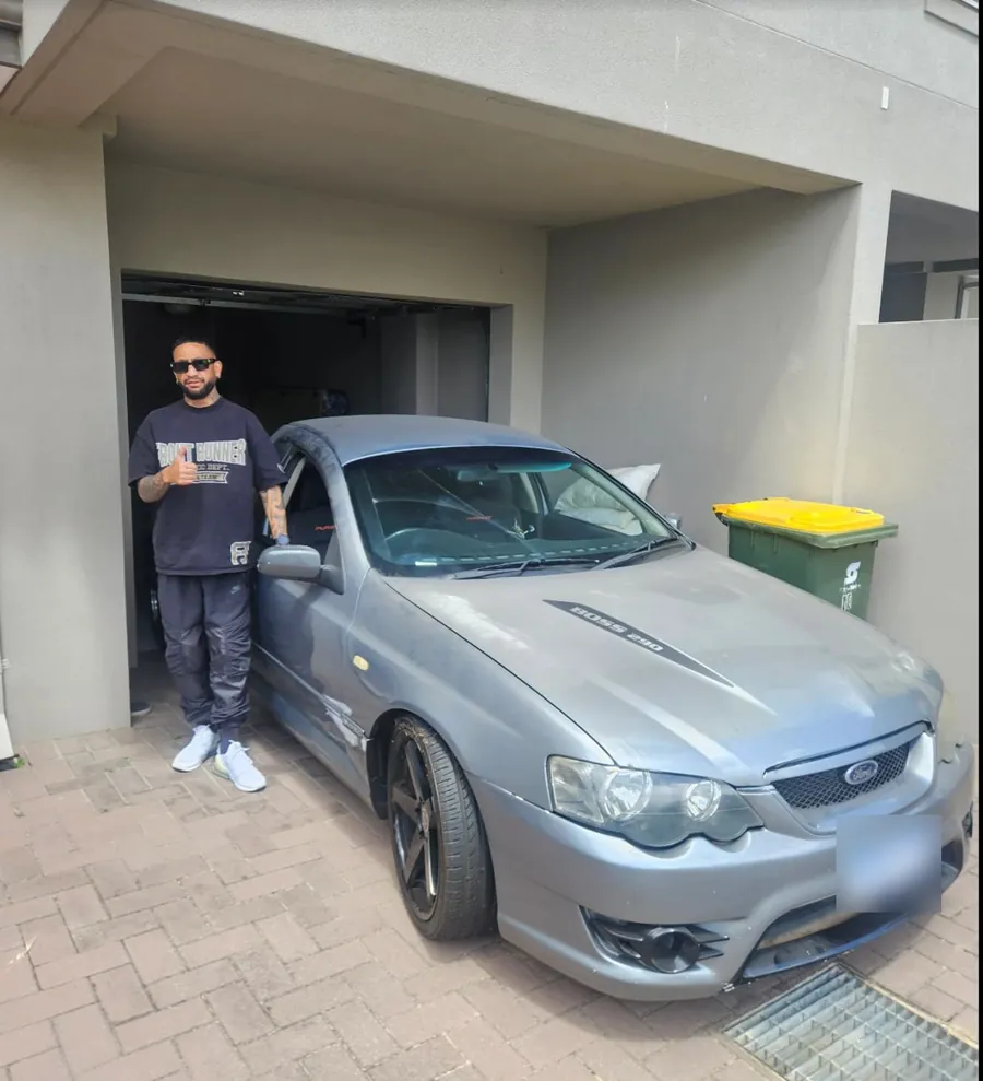 Customer gives a thumbs up beside his grey Ford Falcon in the garage at his Inglewood home after the tow