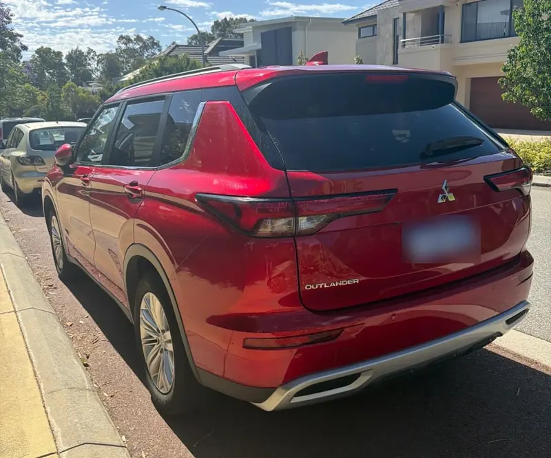 Red Mitsubishi Outlander hire car parked back at the holiday accommodation after the tow