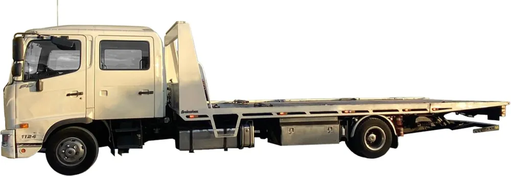 White crew-cab tilt tray tow truck with a long, wide steel deck