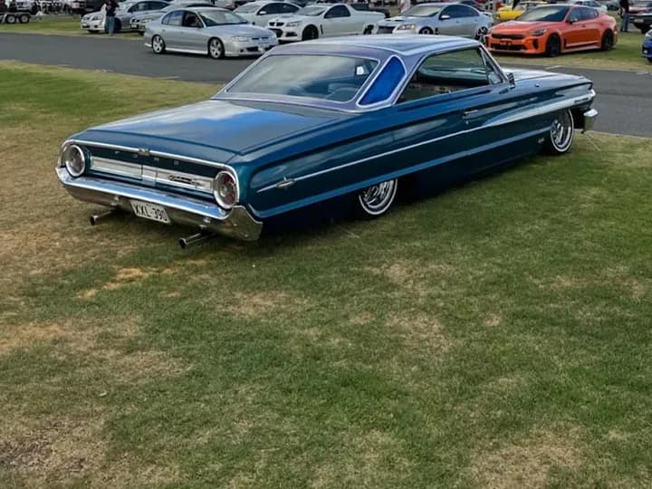 Blue classic Ford Galaxie coupe on the grass at a car show