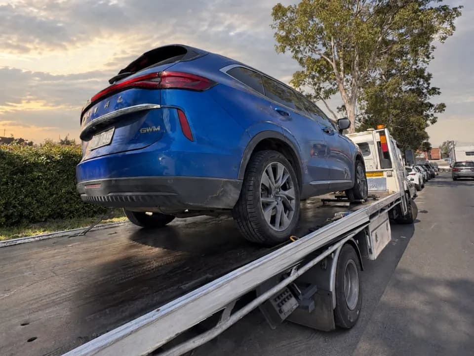 Blue GWM Haval SUV loaded on a tilt tray at sunset
