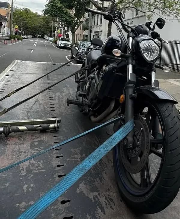 Black cruiser motorcycle strapped down on a tilt tray
