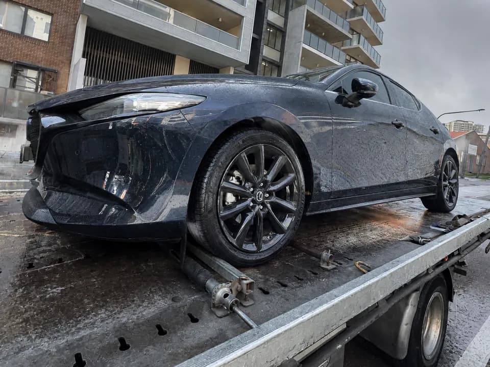 Quokka Towing tilt tray carrying a black hatchback with front-end damage