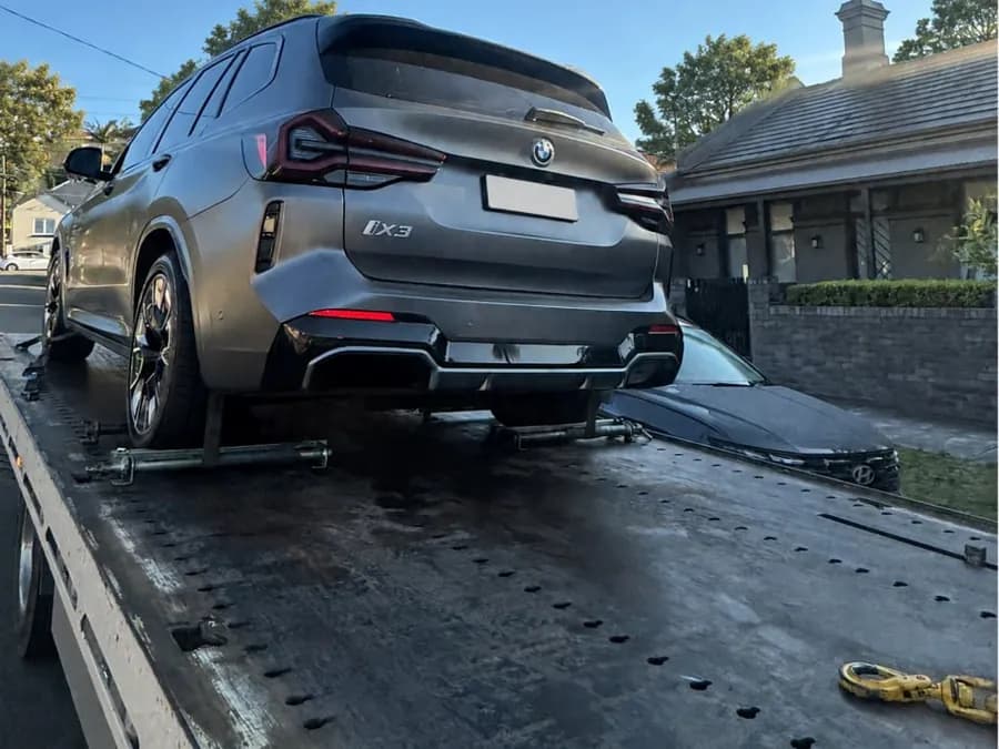 Quokka Towing tilt tray carrying a grey BMW iX3 on a suburban street