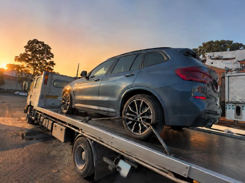 Quokka Towing tilt tray carrying a grey BMW SUV at sunset