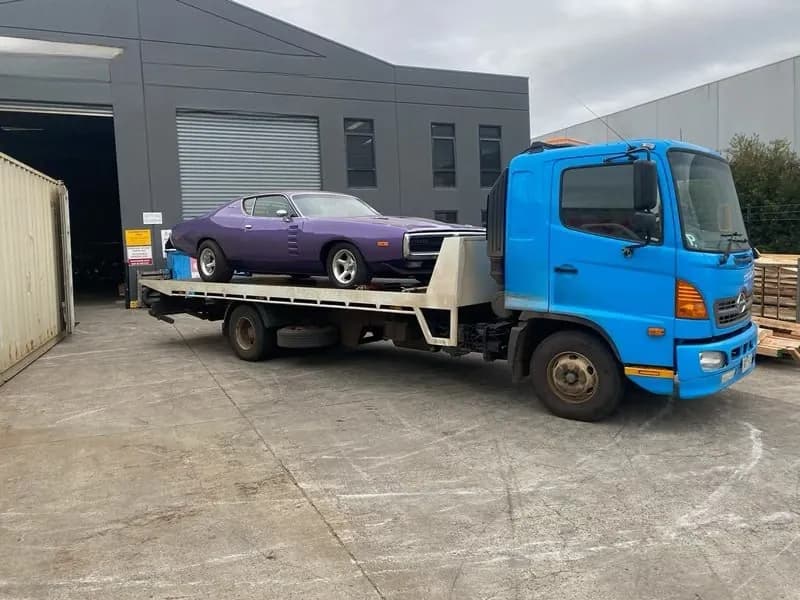 Quokka Towing tilt tray carrying a purple muscle car outside a warehouse