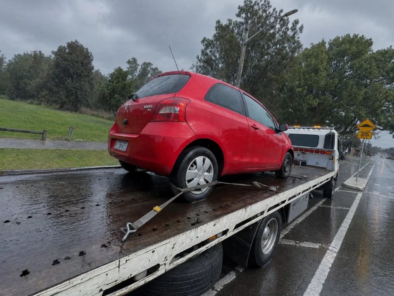Quokka Towing tilt tray carrying a red Toyota Yaris strapped down in the rain