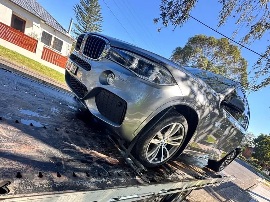 Quokka Towing tilt tray with a silver BMW X5 loaded beside a grass verge