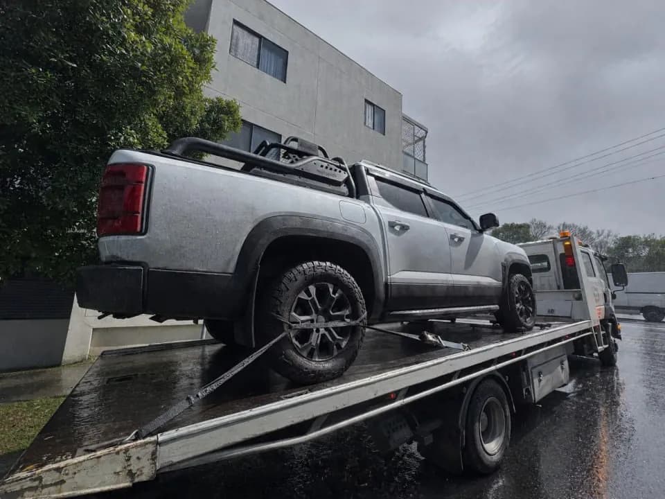 Quokka Towing tilt tray carrying a silver dual-cab ute in the rain