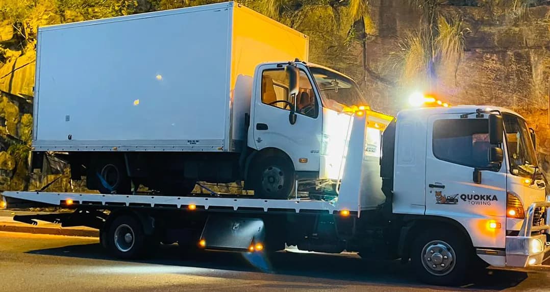 Quokka Towing tilt tray carrying a white box truck at night