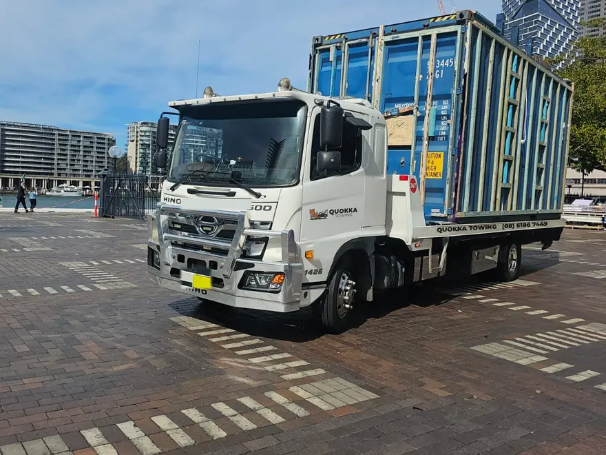 Blue open-frame shipping container on a Quokka Towing tilt tray