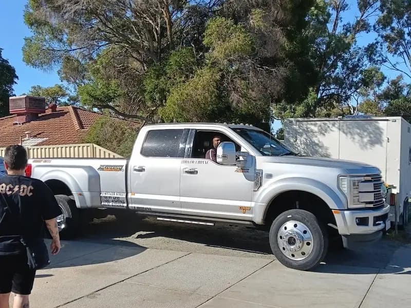 Silver Ford F-450 wheel-lift tow truck parked on a driveway