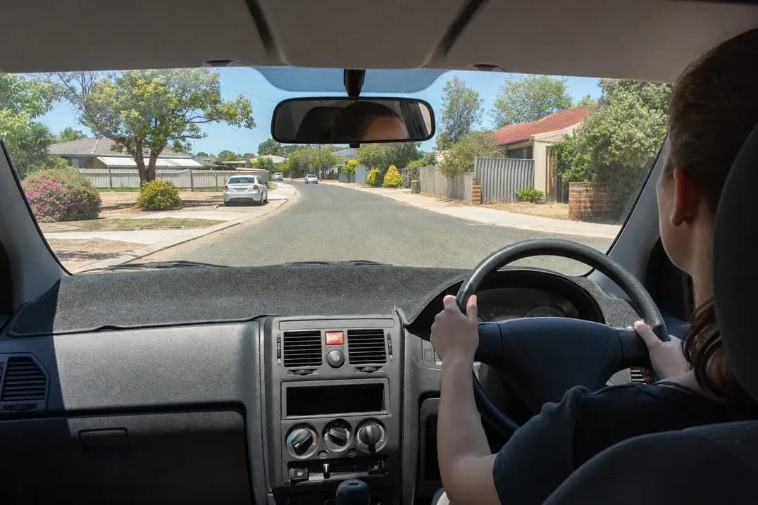 Driver's view through the windscreen of a quiet suburban street