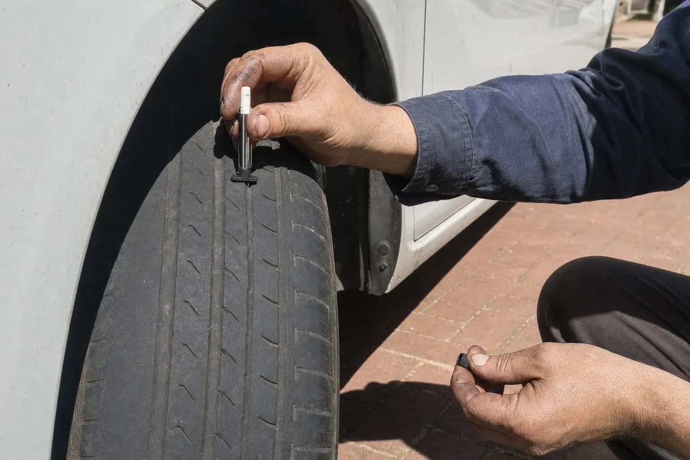 Tread depth gauge pressed into the groove of a car tyre