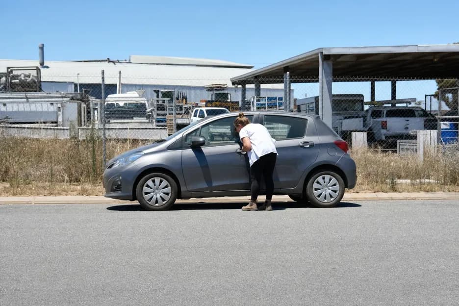 Woman peering through the driver's window of her locked hatchback